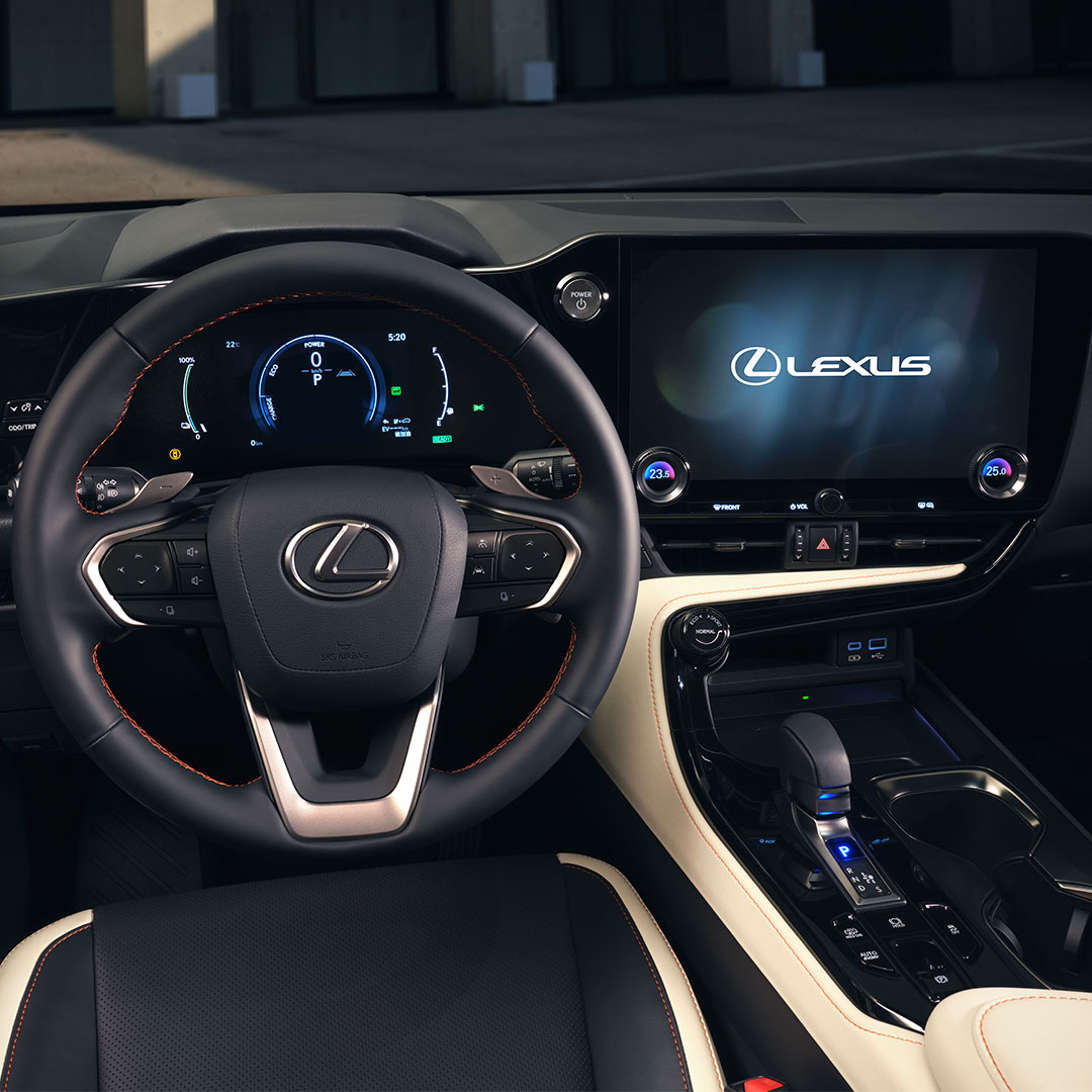 Steering wheel of the new NX appears, with the dashboard and multimedia screens alight behind it.