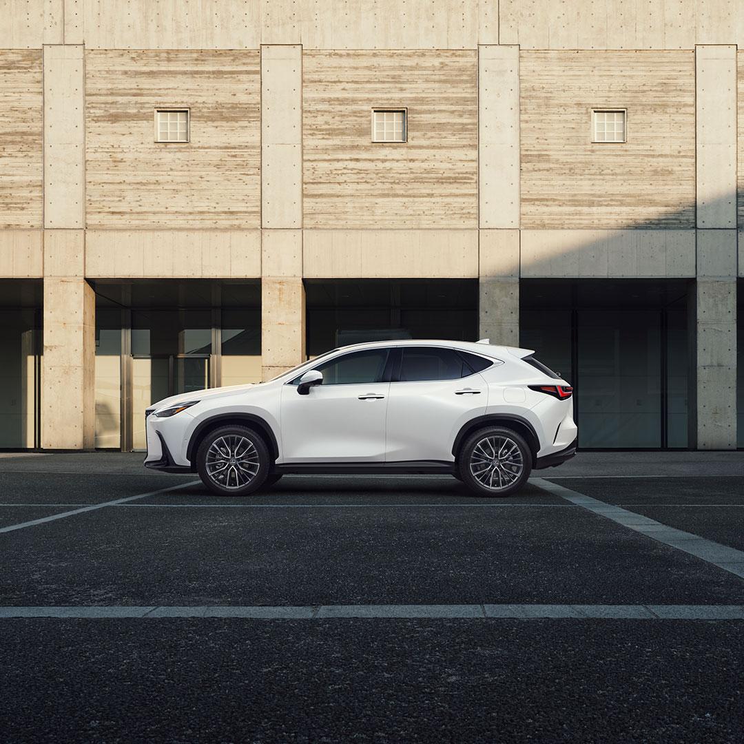 Side on view of the all new Lexus NX in a carpark with a building framed behind