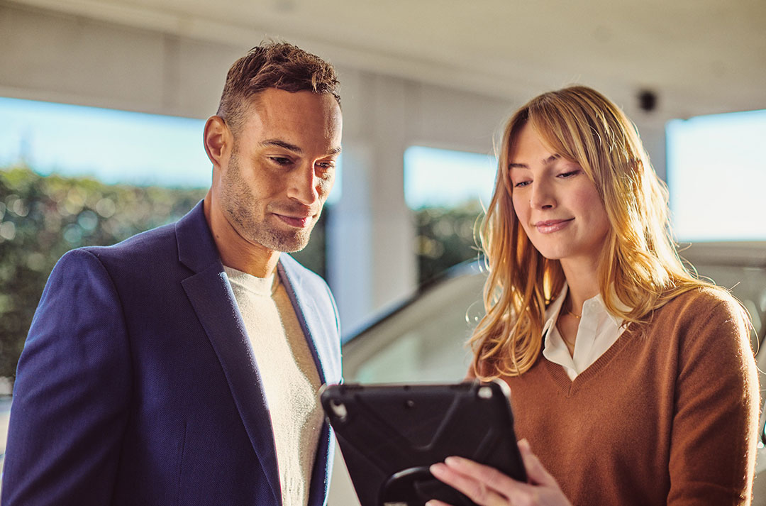 Two people look at a tablet together at a Lexus dealership
