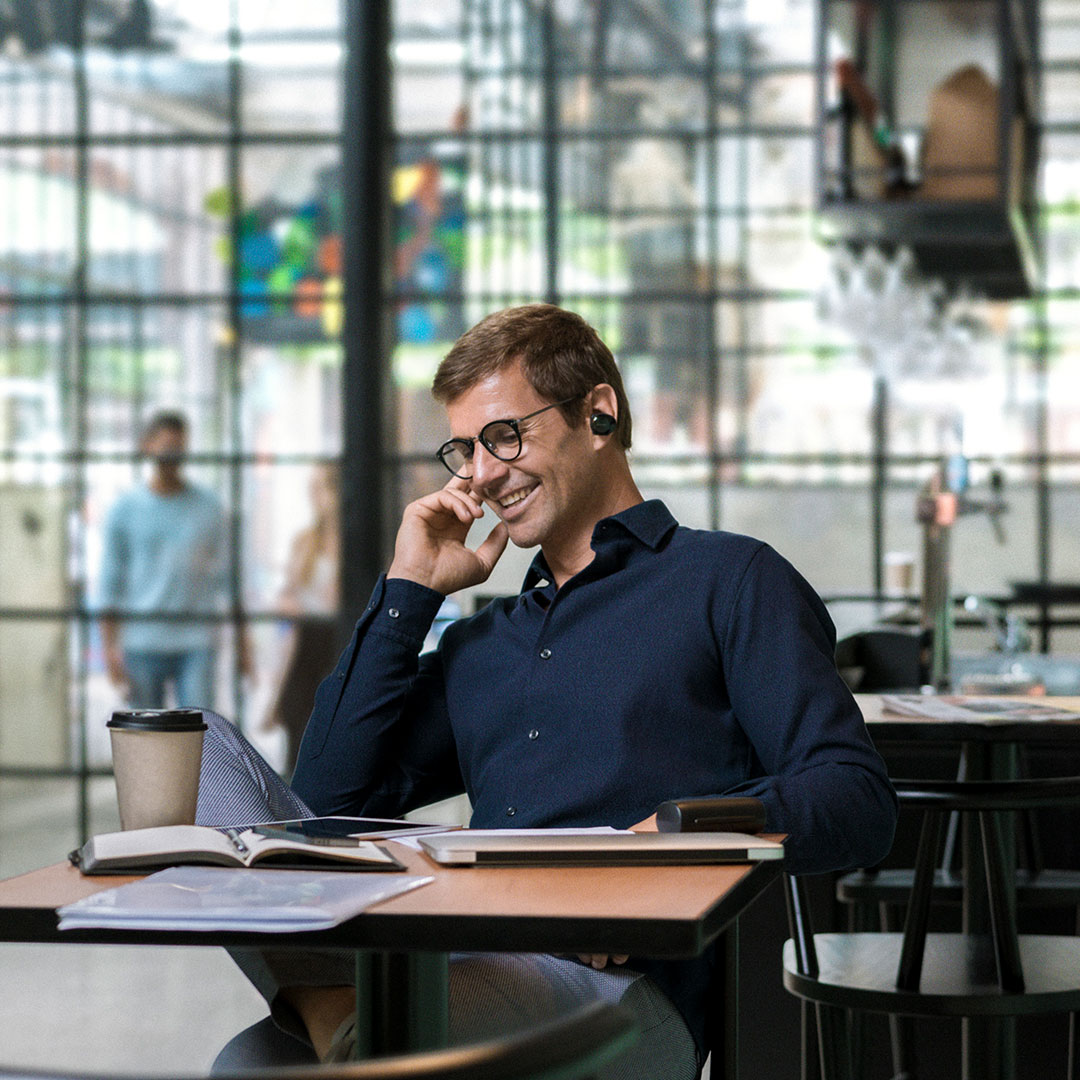 Business man talking into bluetooth headset, smiling at a Lexus dealership
